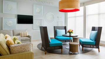 A modern living room with wicker furniture, a flat-screen TV, and artwork on the walls.