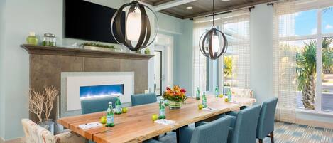 A conference room with a long table, blue chairs, a fireplace, and a TV mounted on the wall.