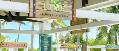 A sign for Salty Lime at Hilton Garden Inn with a menu board below listing items like Rooster, Conch, and Key Lime.