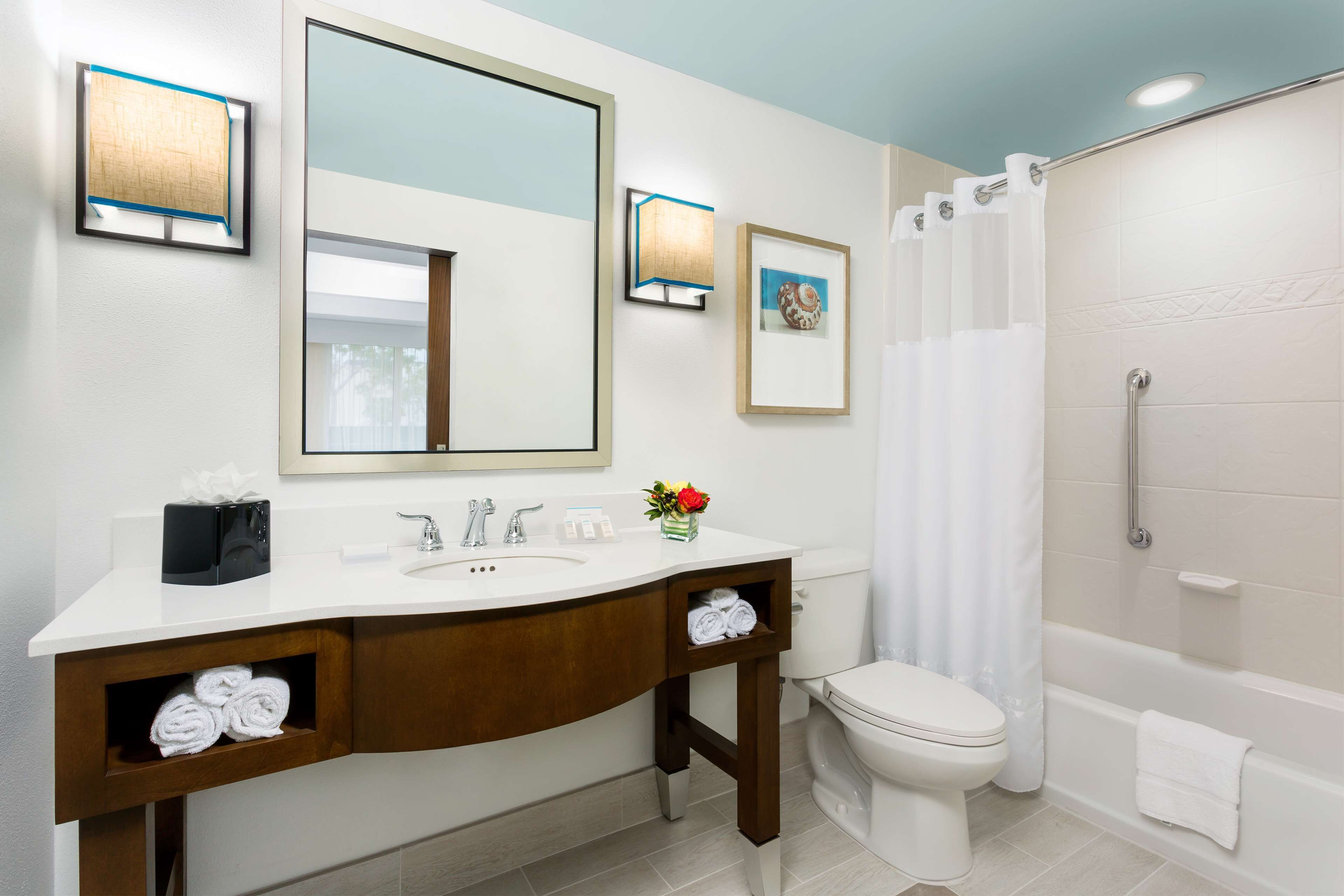 A modern bathroom with a white sink, two towel racks, a toilet, and a shower area.