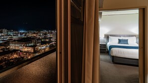 A hotel room with a city view, a bed, and a night-time cityscape visible through the window. - Kingsgate Hotel Dunedin (Dunedin)