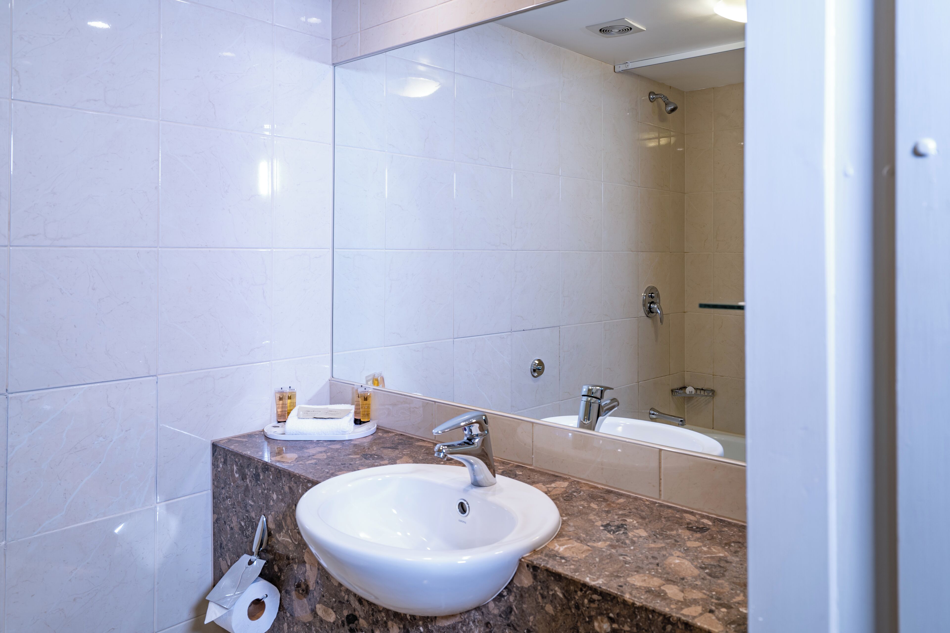 A bathroom with a marble sink, a toilet, and a shower.