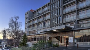 A multi-story hotel with a prominent Kingsgate Hotel sign, large windows, and a visible staircase leading to the upper floors. - Kingsgate Hotel Dunedin (Dunedin)