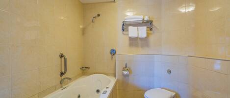 Un baño con bañera, inodoro y toallero con toallas.