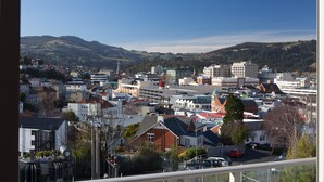 A cityscape with a mix of residential and commercial buildings, a prominent church, and rolling hills in the background. - Kingsgate Hotel Dunedin (Dunedin)