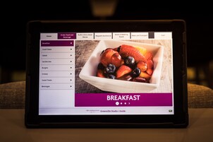 Un tablet mostra un menù della colazione con proposte come piccoli piatti, insalate e panini.