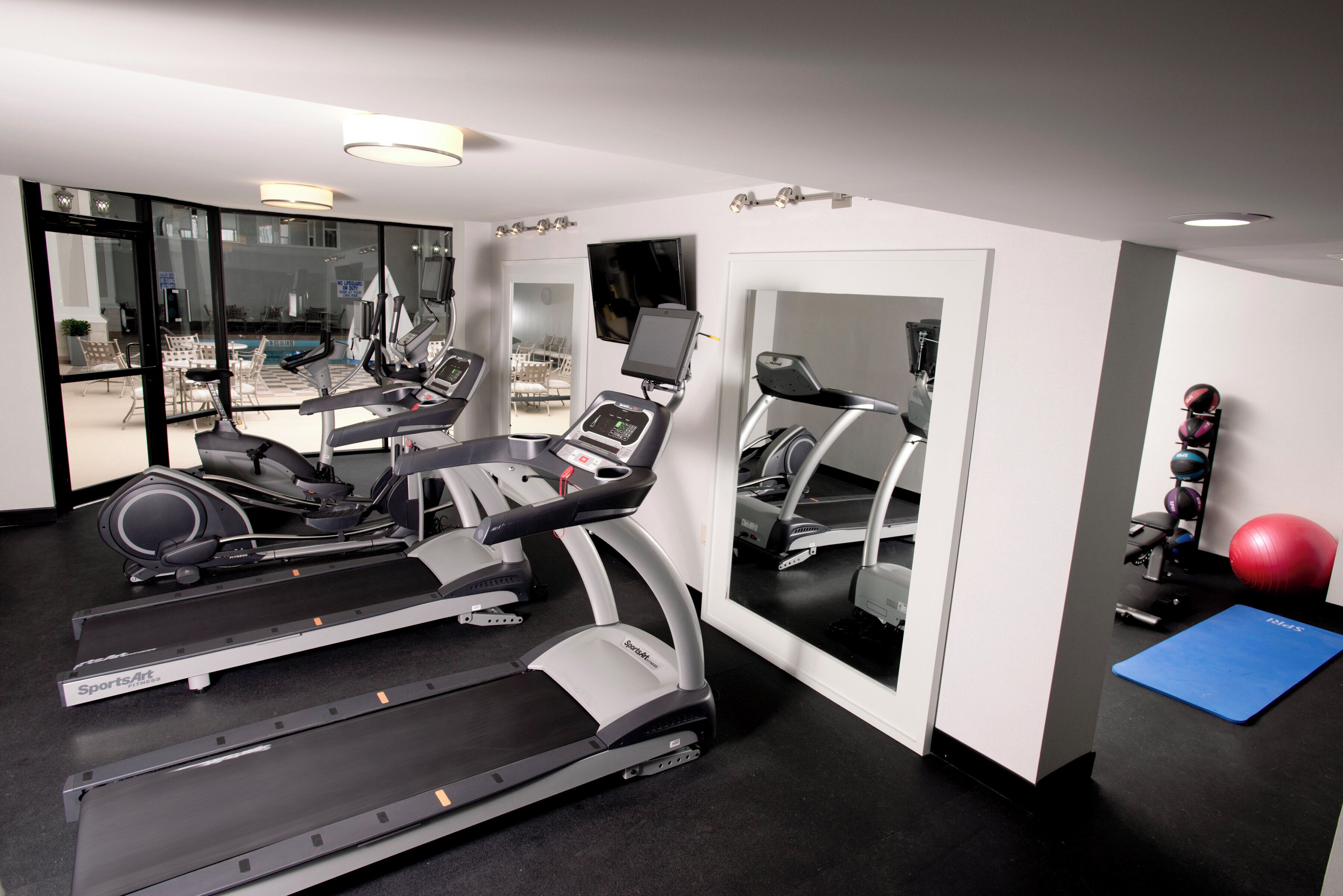 A gym with treadmills, stationary bikes, and exercise balls.