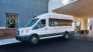 Un fourgon blanc est garé devant un immeuble sur lequel on peut lire les inscriptions « CROWNE PLAZA » et « GAGEMENT LIBRE 13 PIEDS 0 POUCES ».