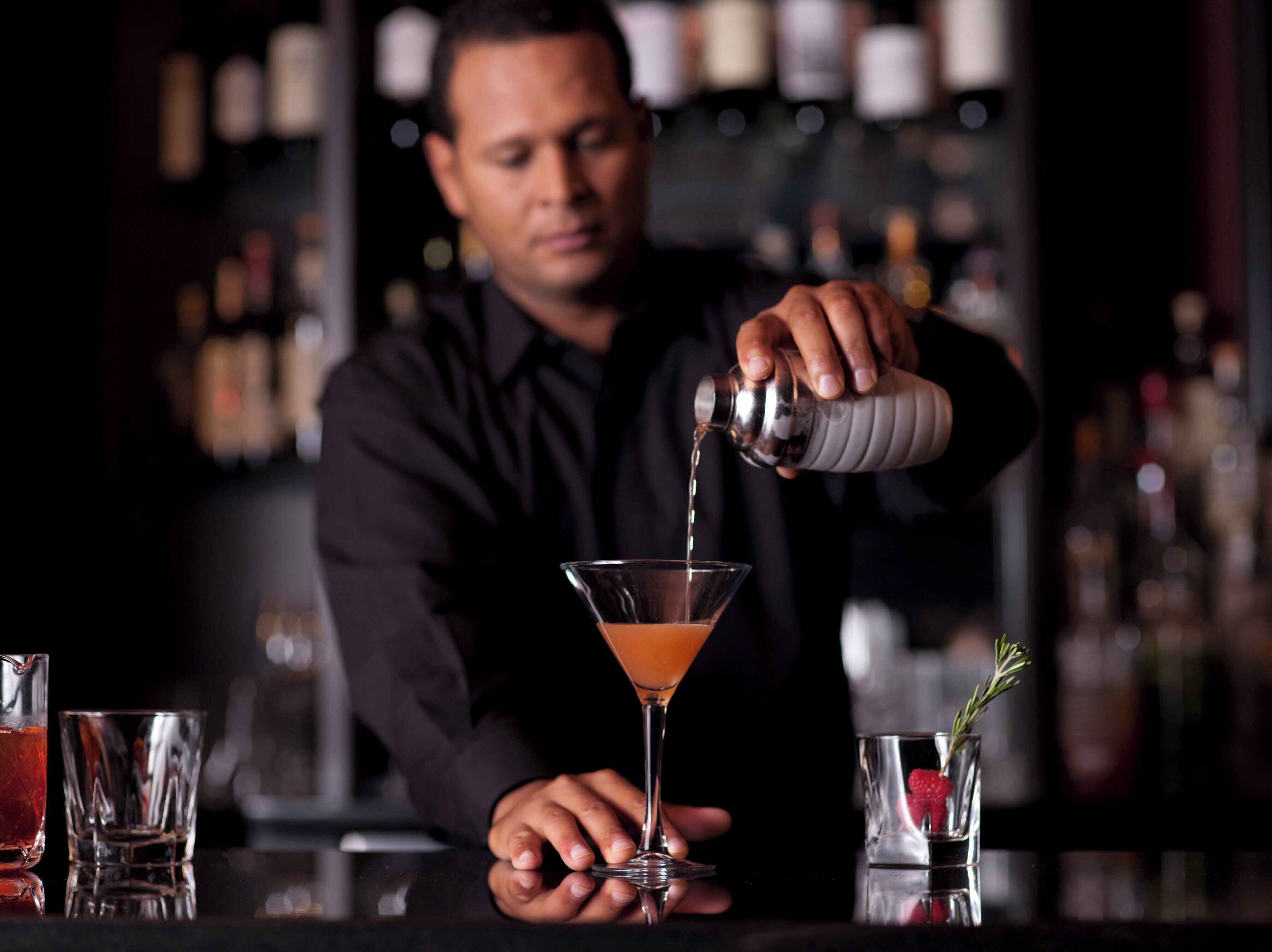 Un cantinero sirve una bebida en una copa de martini.