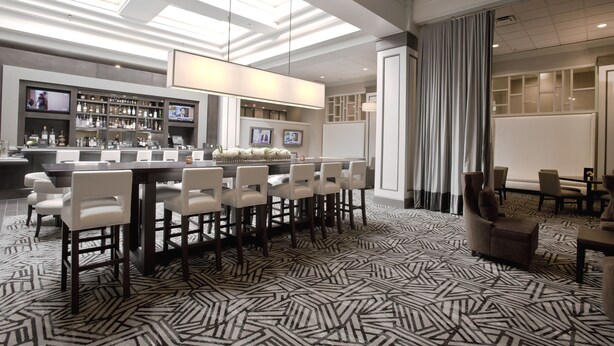 A modern hotel lobby with a bar area, seating, and a patterned floor. - Crowne Plaza Hotel Greenville-I-385-Roper Mtn Rd by IHG (Greenville)