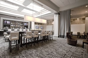 A modern hotel lobby with a bar area, seating, and a patterned floor. - Crowne Plaza Hotel Greenville-I-385-Roper Mtn Rd by IHG (Greenville)
