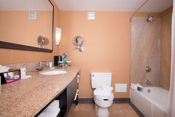 A bathroom with a granite countertop sink, a toilet, a shower, and a mirror. - Crowne Plaza Hotel Greenville-I-385-Roper Mtn Rd by IHG (Greenville)