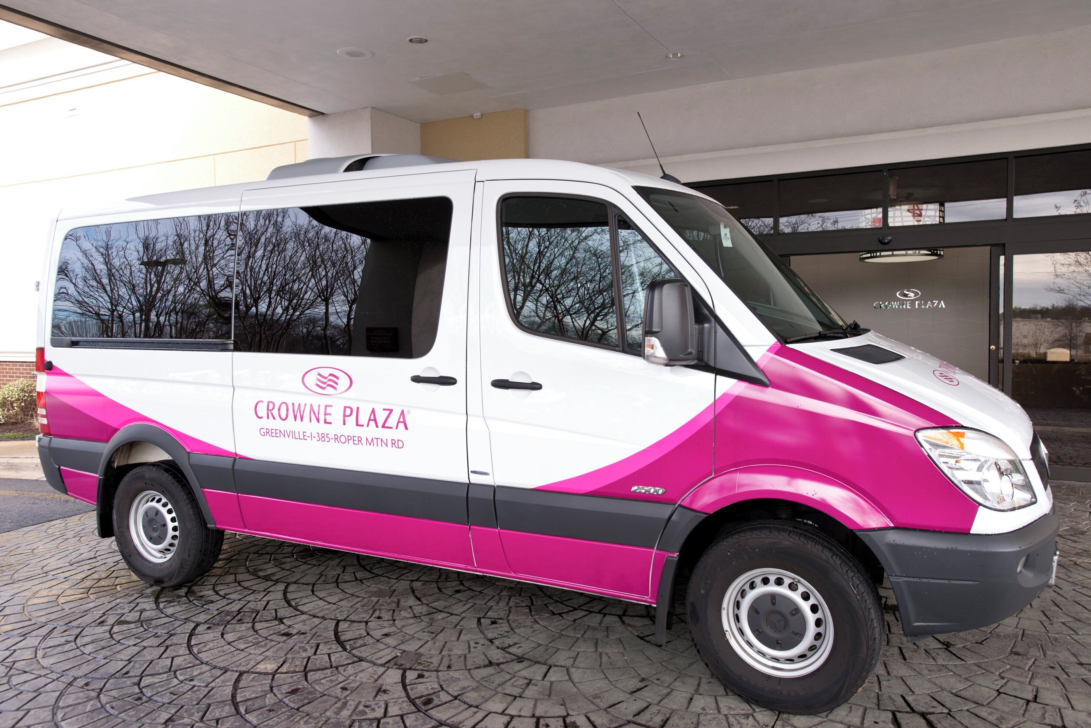 A white and pink van with 'CROWNE PLAZA' branding parked outside a building.