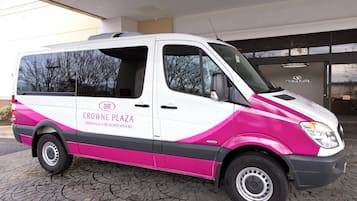 A white and pink van with 'CROWNE PLAZA' branding parked outside a building.