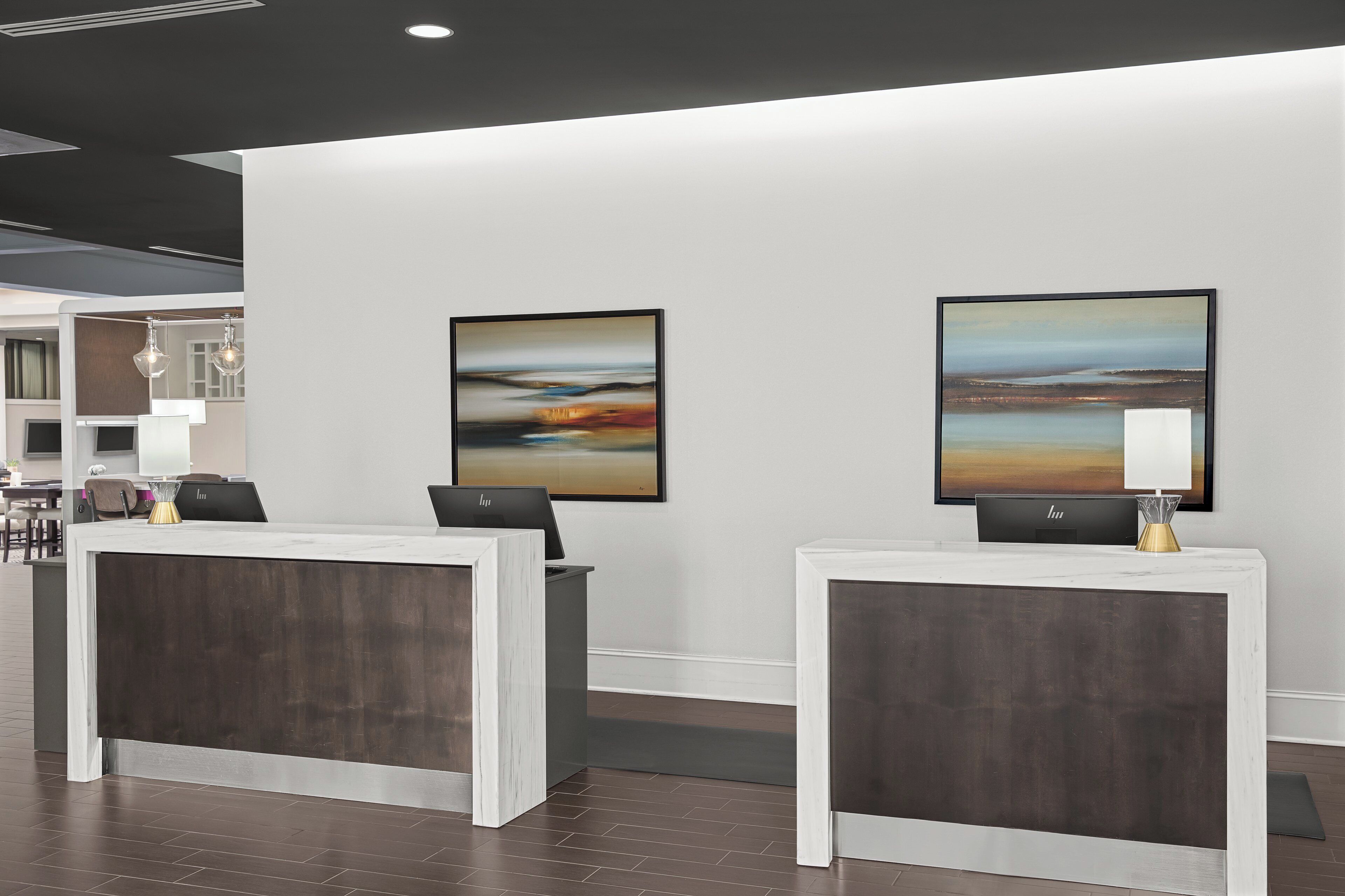 A reception area with two reception desks, a wall-mounted painting, and a modern interior design.
