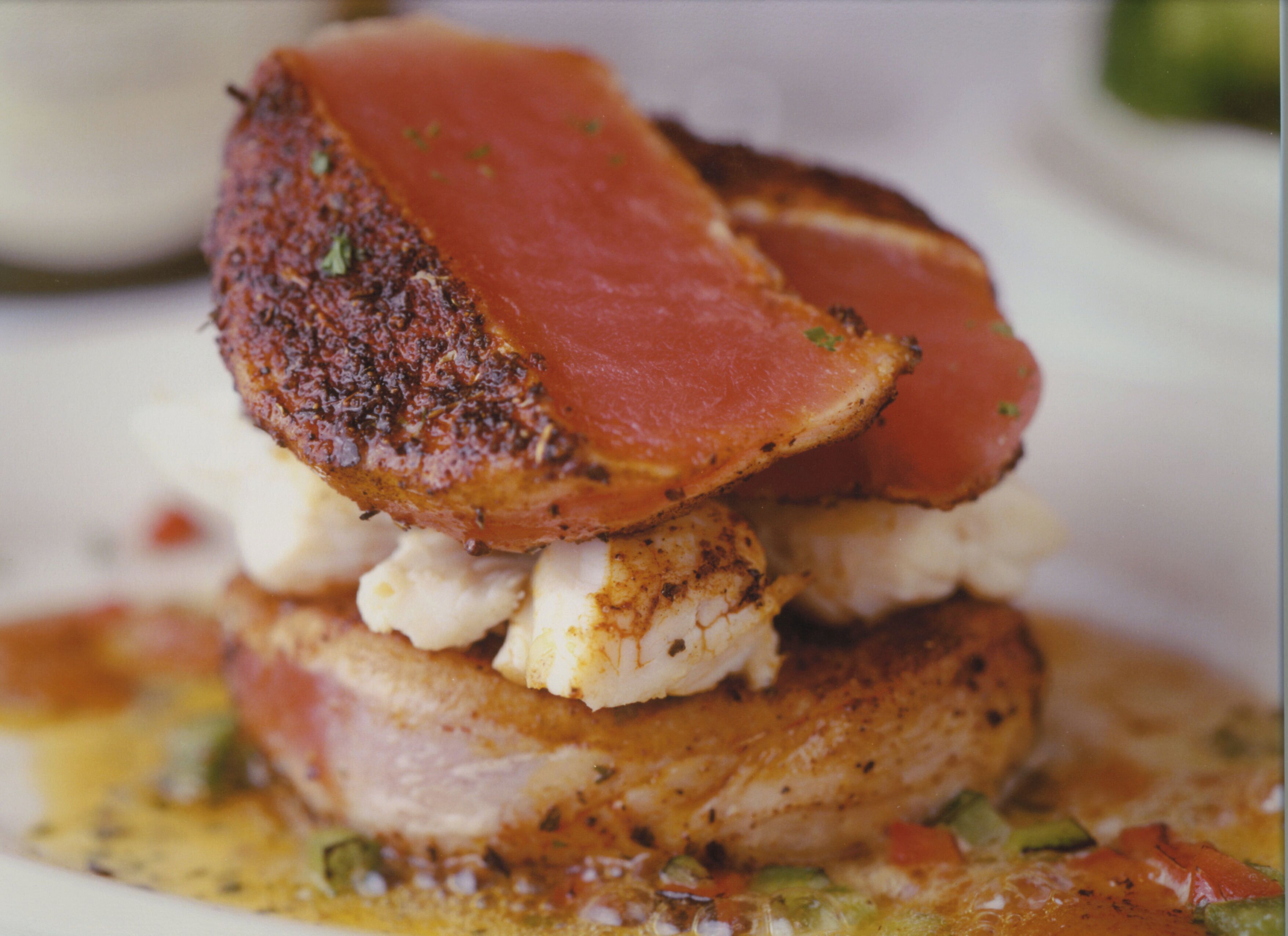 A stack of food items including a piece of meat, a slice of bread, and a white cheese.