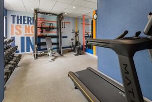 Uma academia com esteira, pesos e equipamentos de ginástica.