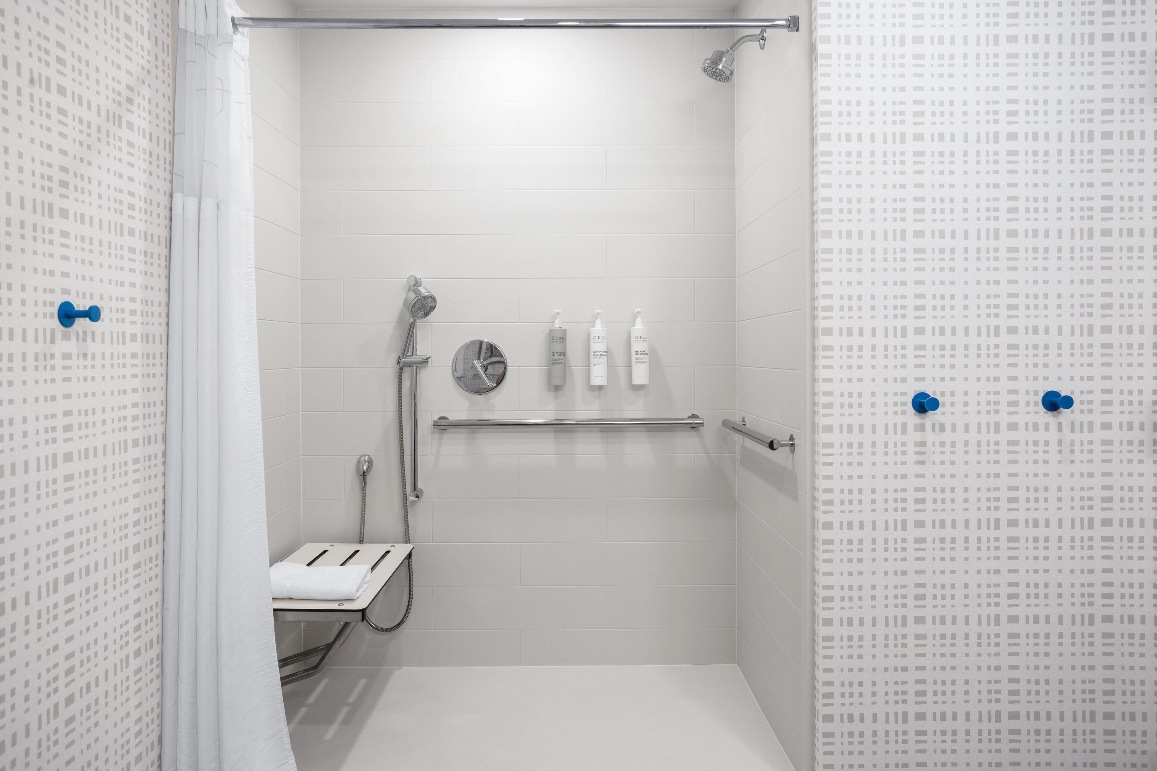 A modern shower area with a handheld showerhead, a wall-mounted faucet, and a glass-enclosed toilet.