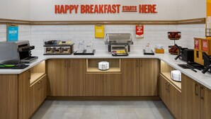 A breakfast station with a sign that reads 'HAPPY BREAKFAST STARTS HERE.' - Hampton Inn Staunton (Staunton)