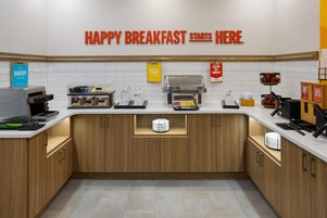 Una estación de desayuno con un cartel que dice 'HAPPY BREAKFAST STARTS HERE'.