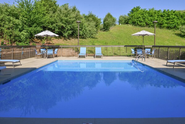 Una piscina al aire libre de temporada, sombrillas