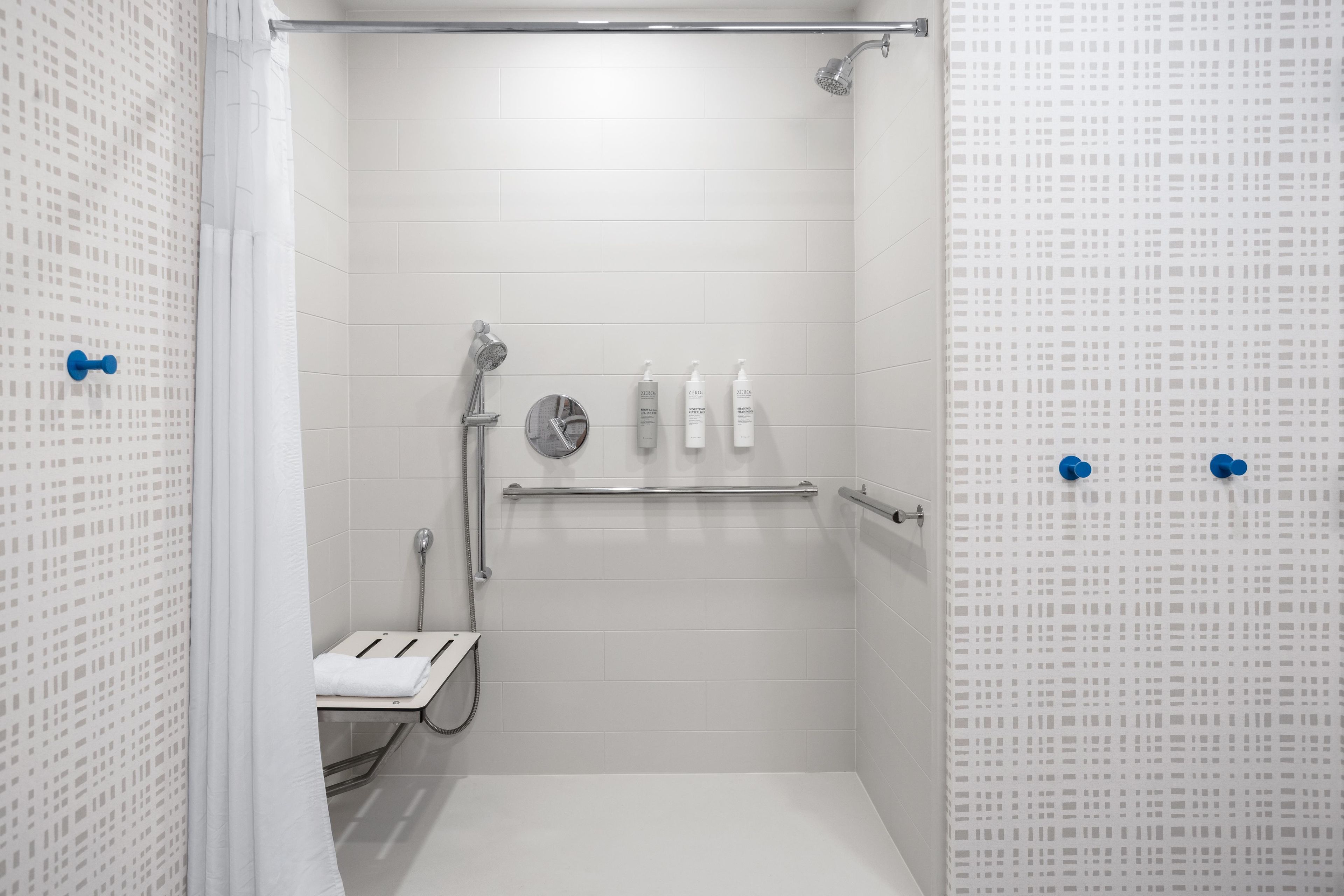 Ein modernes Duschbad mit Handbrause, Wandarmatur und einer Toilette mit Glasabtrennung.