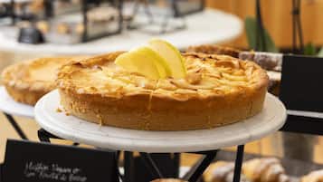 Une table où sont présentés des desserts, notamment un gâteau et des muffins, avec un panneau indiquant les options végétaliennes.