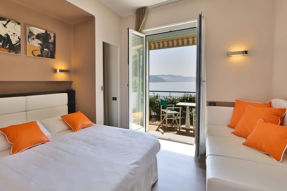 A hotel room with a large bed, a balcony with a table and chairs, and artwork on the walls.