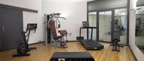 Un gimnasio con equipo de ejercicio que incluye una cinta de correr, bicicletas estáticas y máquinas de pesas.