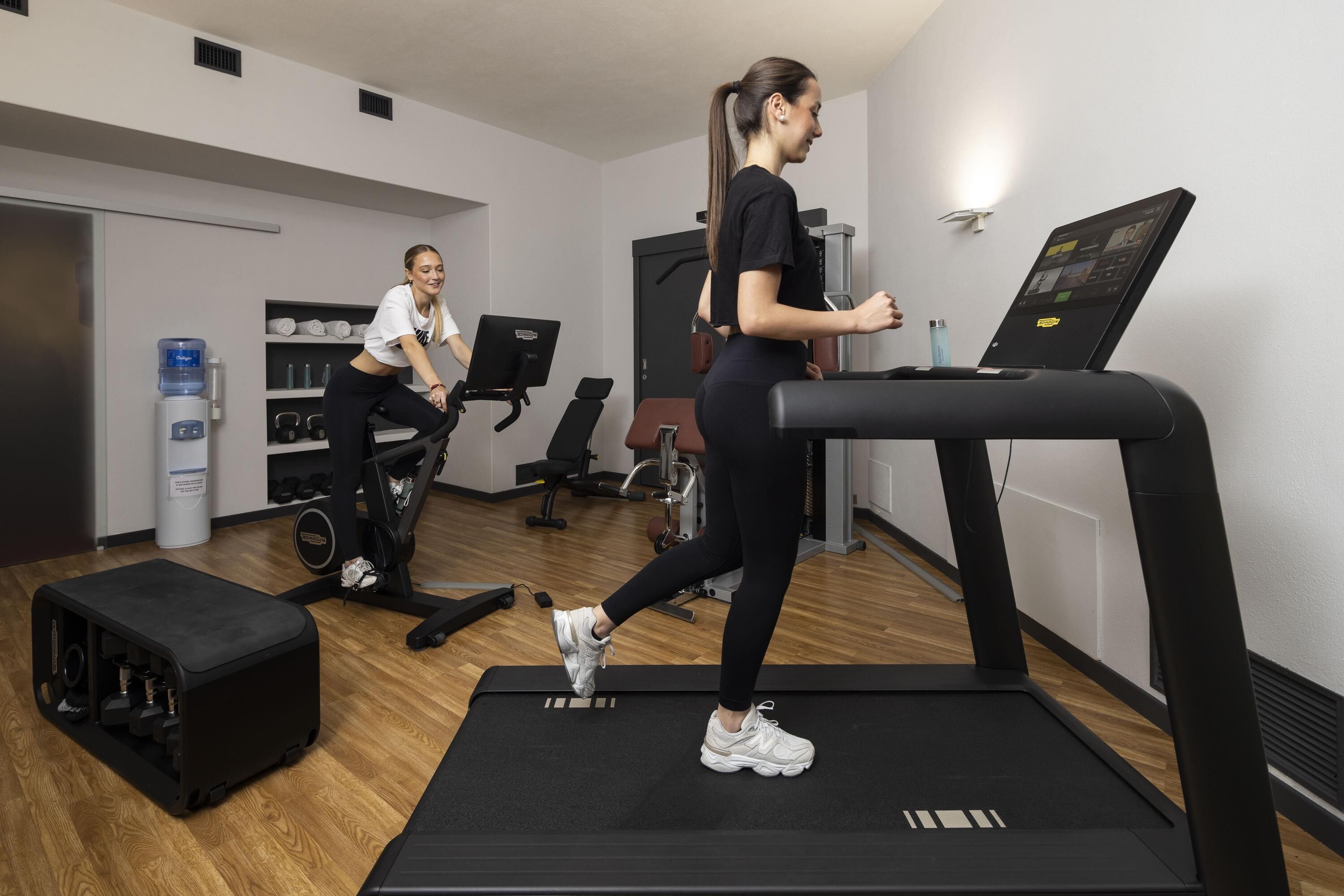 Una palestra con tapis roulant, un distributore d'acqua e attrezzature per esercizi.