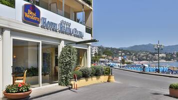 A hotel with a balcony, large windows, and a view of the sea.