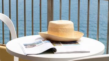 A balcony with a white table, a straw hat, and a magazine.