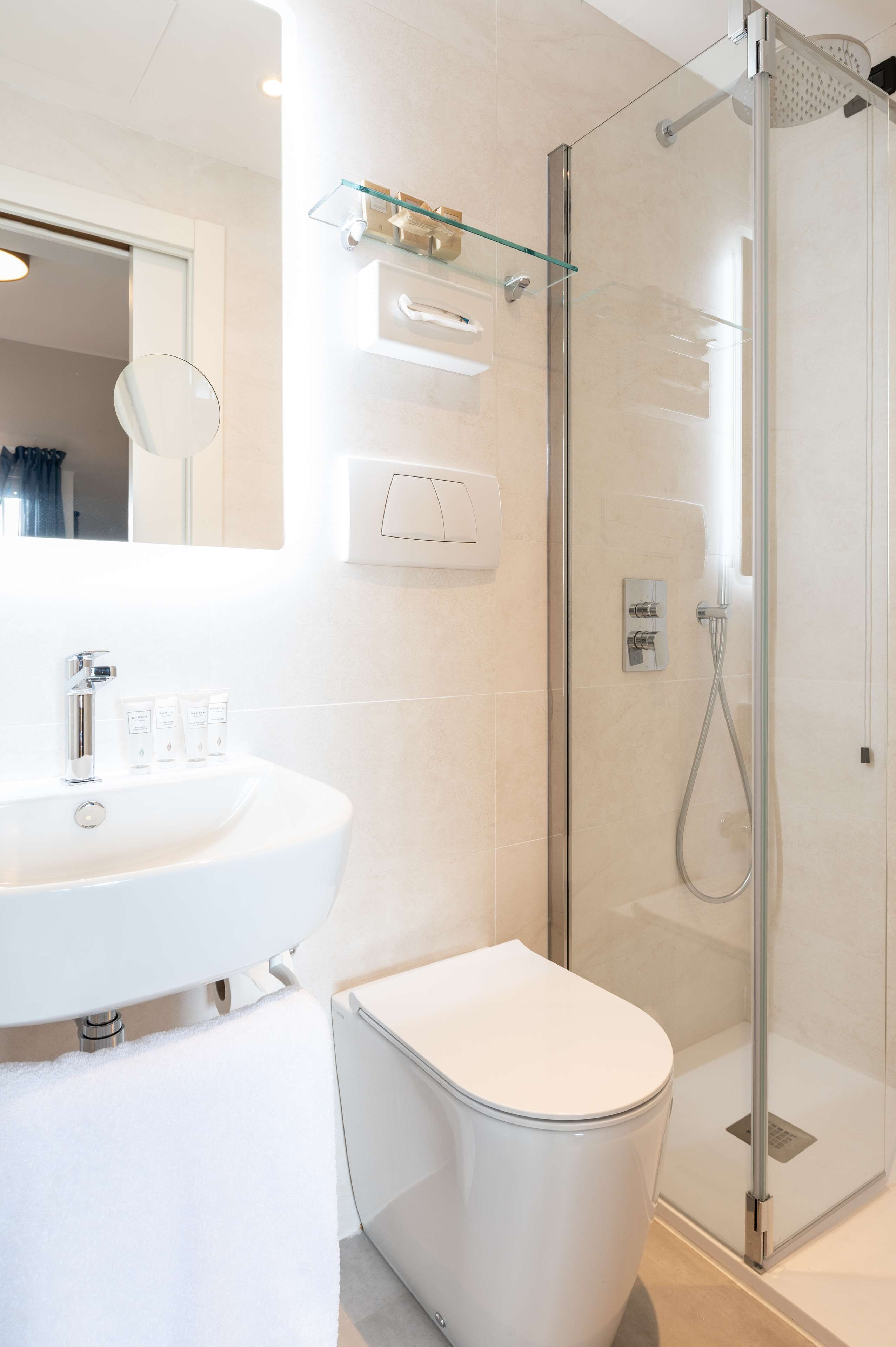 A modern bathroom with a glass-enclosed shower, a white sink, and a toilet.