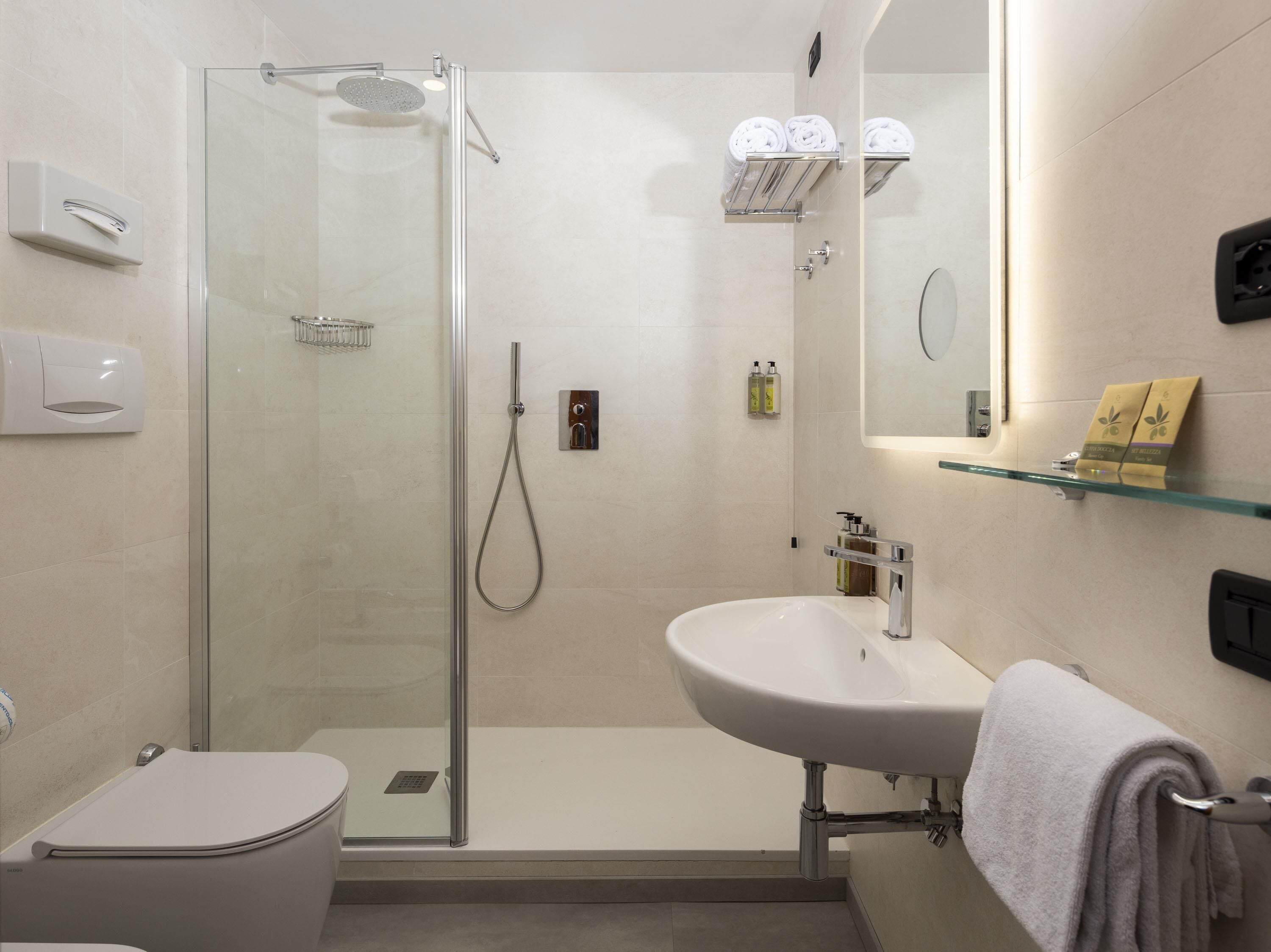 Ein modernes Badezimmer mit einer gläsernen Dusche, einem weißen Waschbecken und einer Toilette.