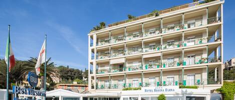 A multi-story hotel with balconies, a sign for Best Western Hotel Regina Elena, and a private beach with an outdoor restaurant.