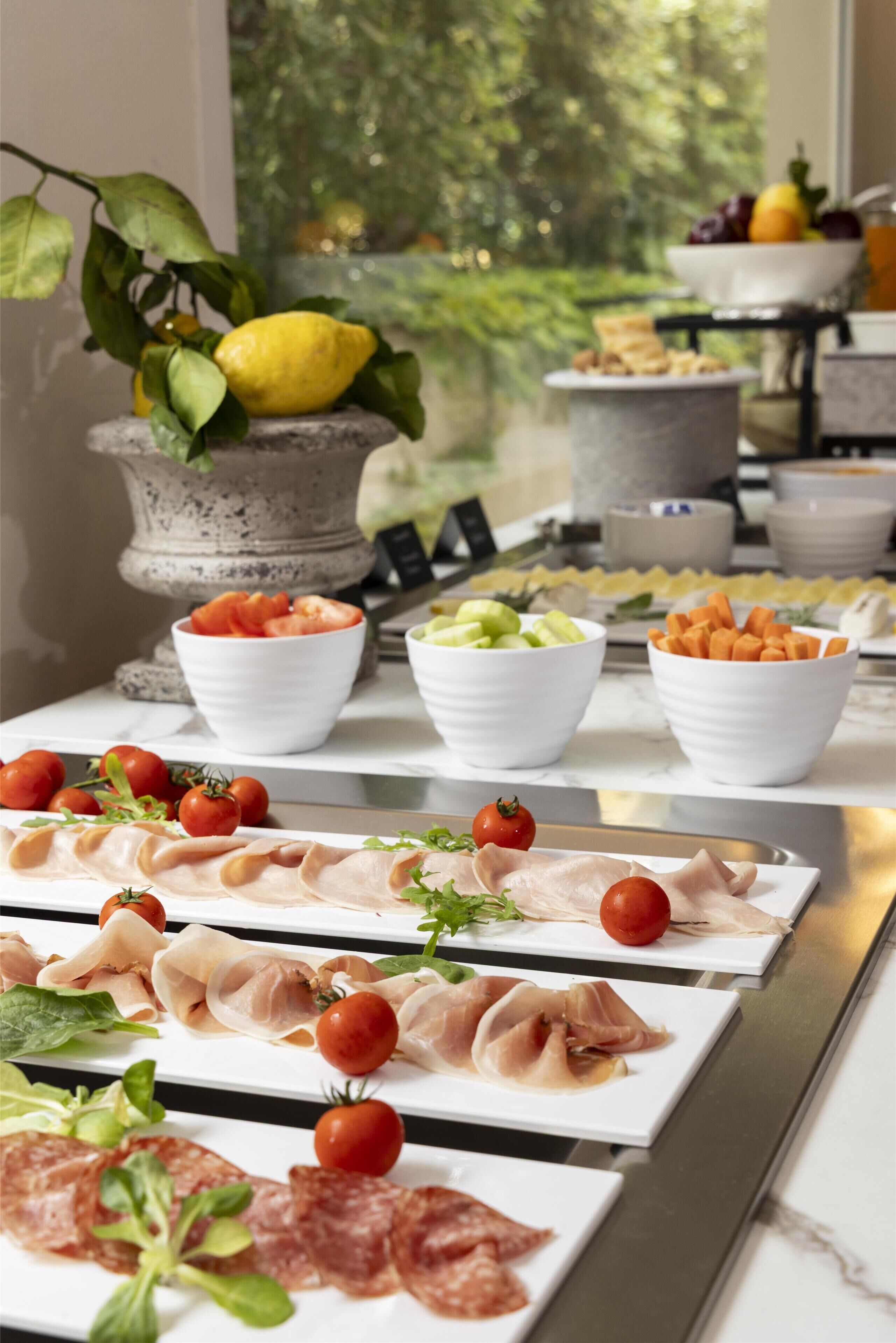 A buffet table with various food items including meats, cheeses, and vegetables.