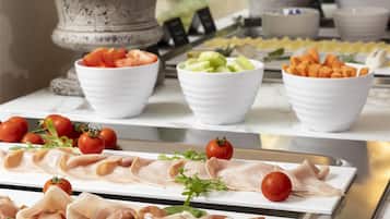 Une table de buffet proposant une variété de plats, notamment des viandes, des fromages et des légumes.