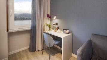Una habitación moderna con escritorio, silla y vista a un cuerpo de agua y montañas.