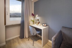 Una habitación moderna con escritorio, silla y vista a un cuerpo de agua y montañas.