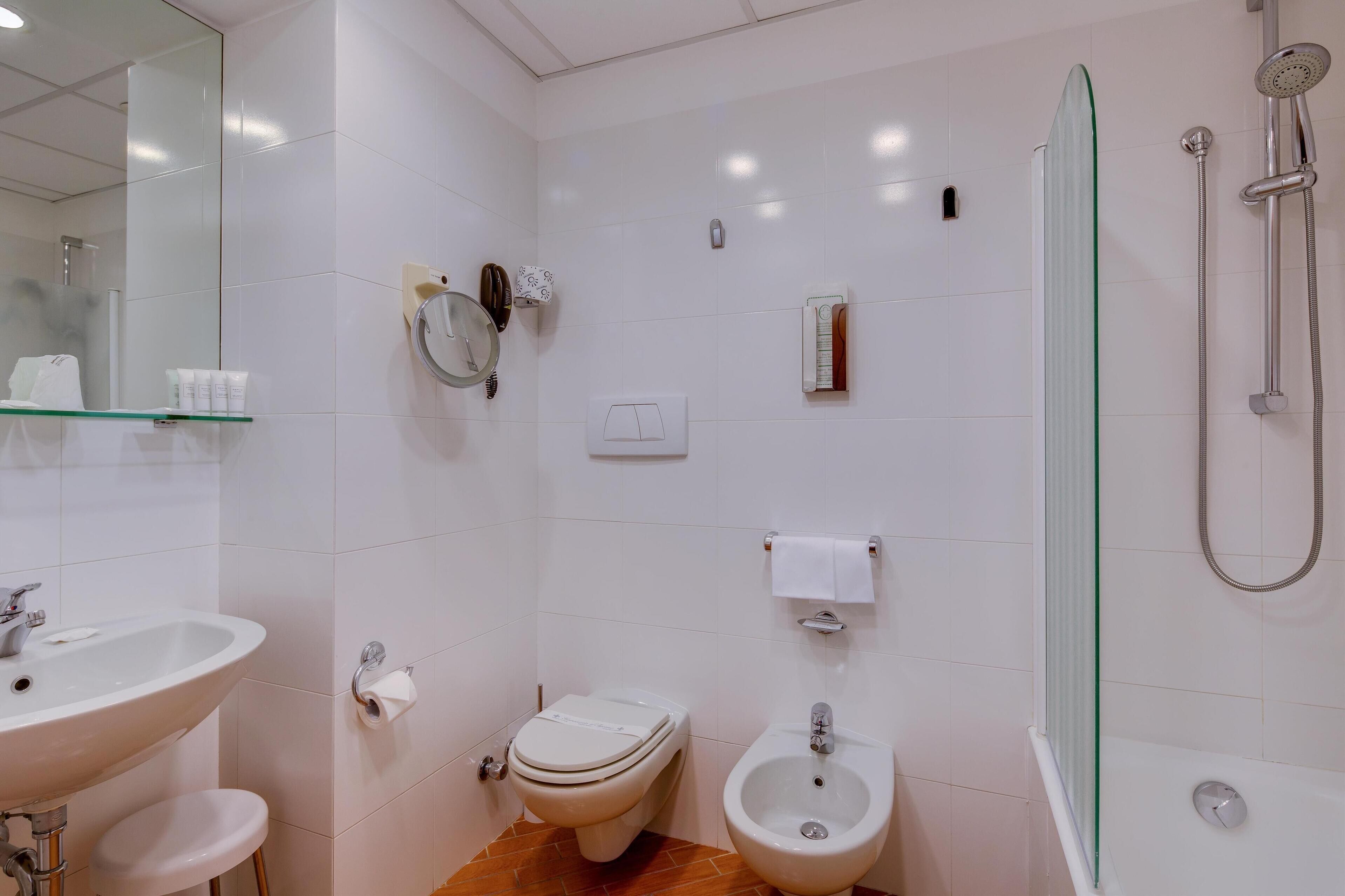 Un bagno con lavandino, water, bidet e doccia.