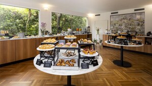 Un buffet de petit-déjeuner proposant une variété de viennoiseries et de desserts, présentés sur des tables et des comptoirs.