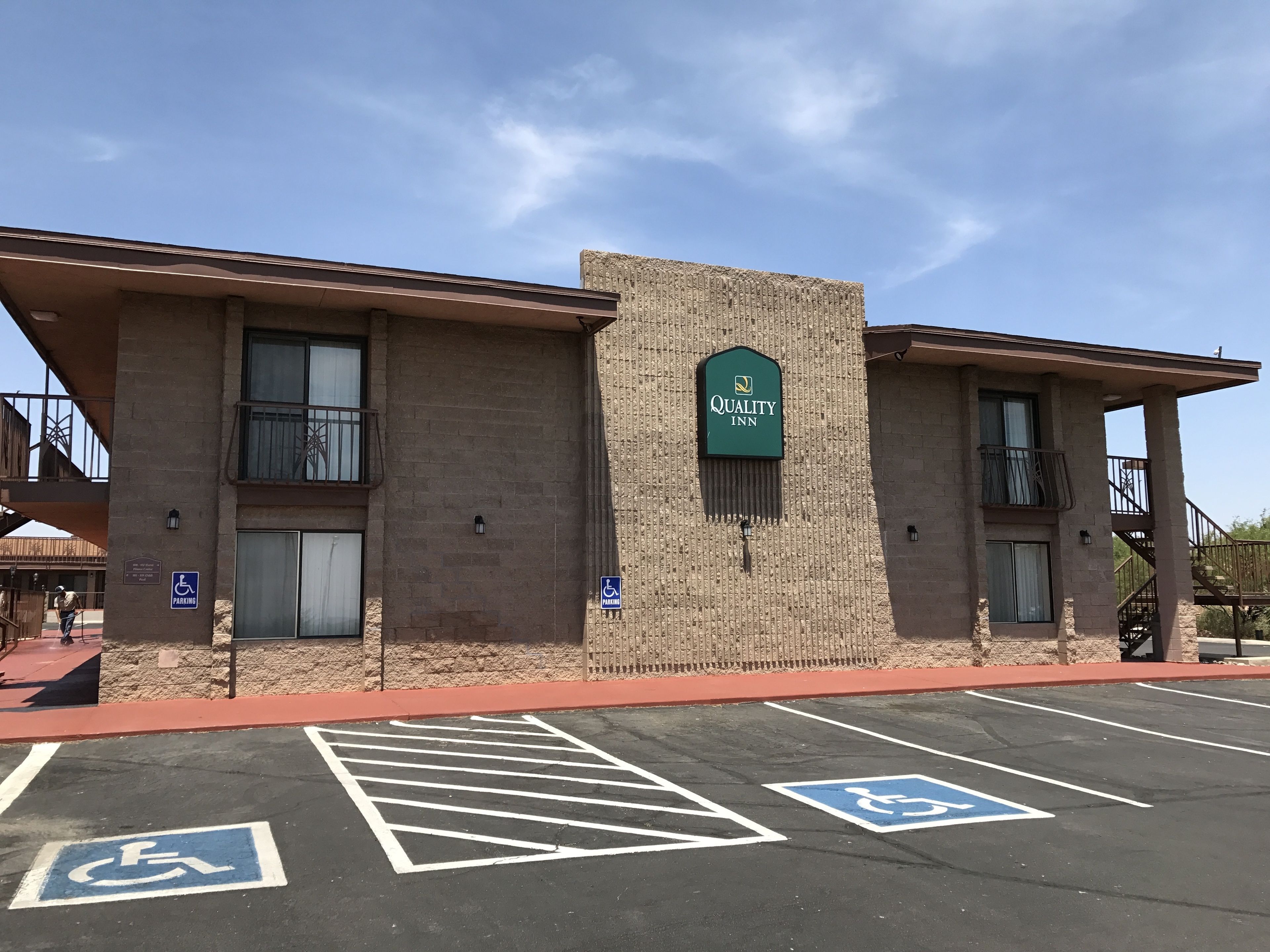 A Quality Inn with a brick facade, a signboard, and designated handicapped parking spaces.