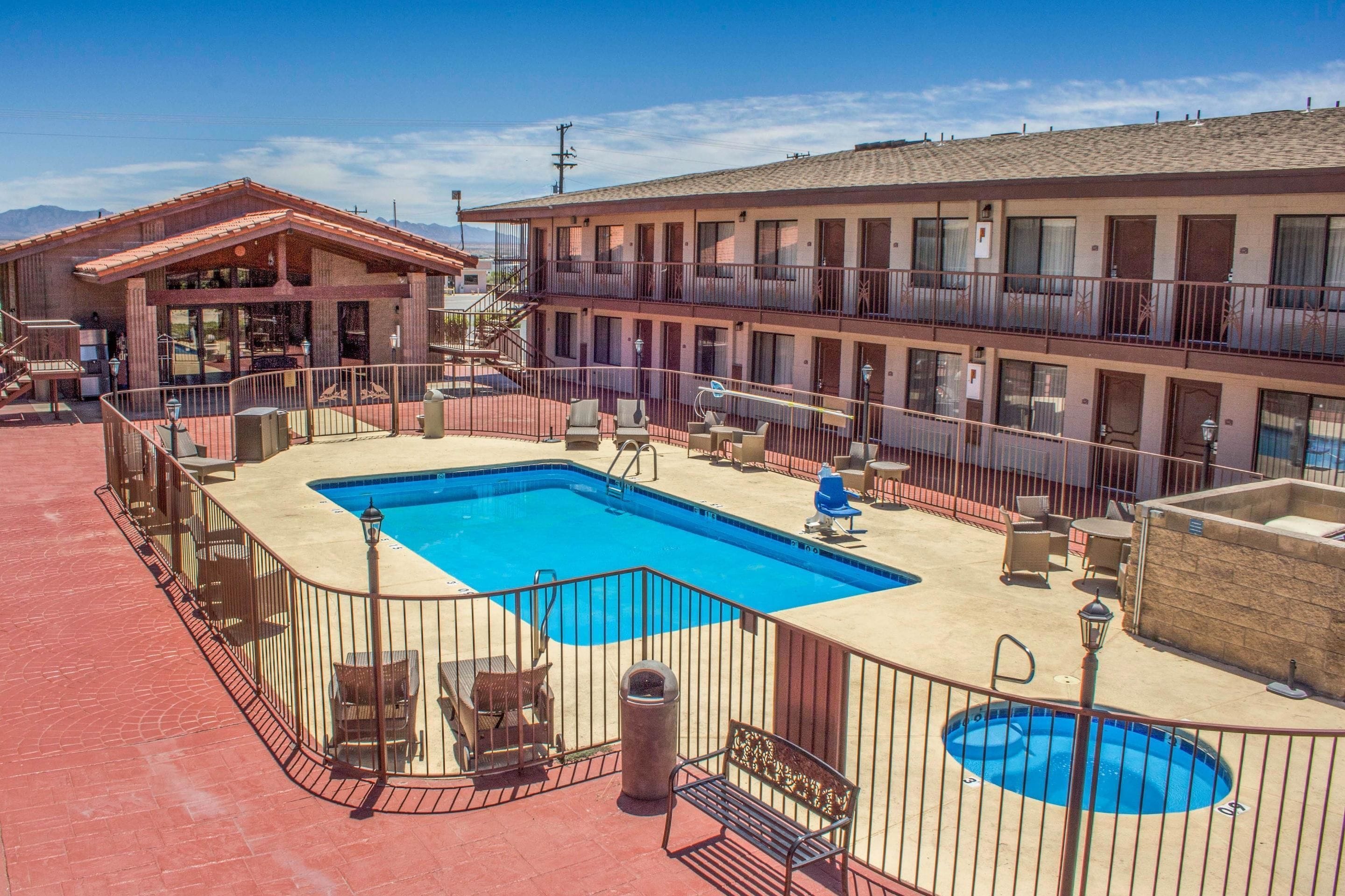 A motel with a pool area, including a large pool, lounge chairs, and a bar.