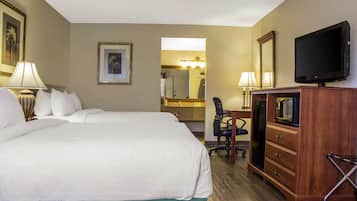 A hotel room with a large bed, a desk with a chair, a television, and a mirror.