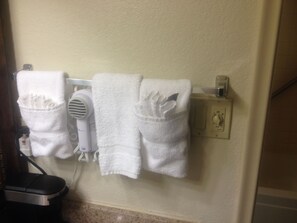 A wall-mounted towel rack with two white towels and a hairdryer.