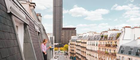Un paysage urbain mêlant architecture moderne et traditionnelle, avec notamment un gratte-ciel imposant et des bâtiments plus anciens dotés de balcons.