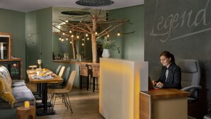 Een modern interieur met een receptiebalie, een zithoek en een decoratieve boomstructuur.