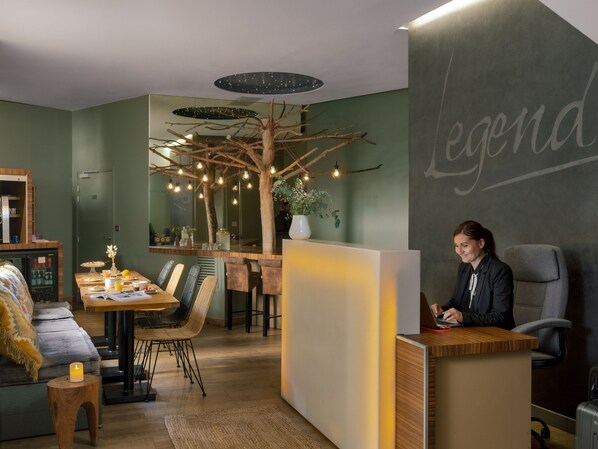 Un interior moderno con mostrador de recepción, zona de estar y una estructura decorativa de árbol.