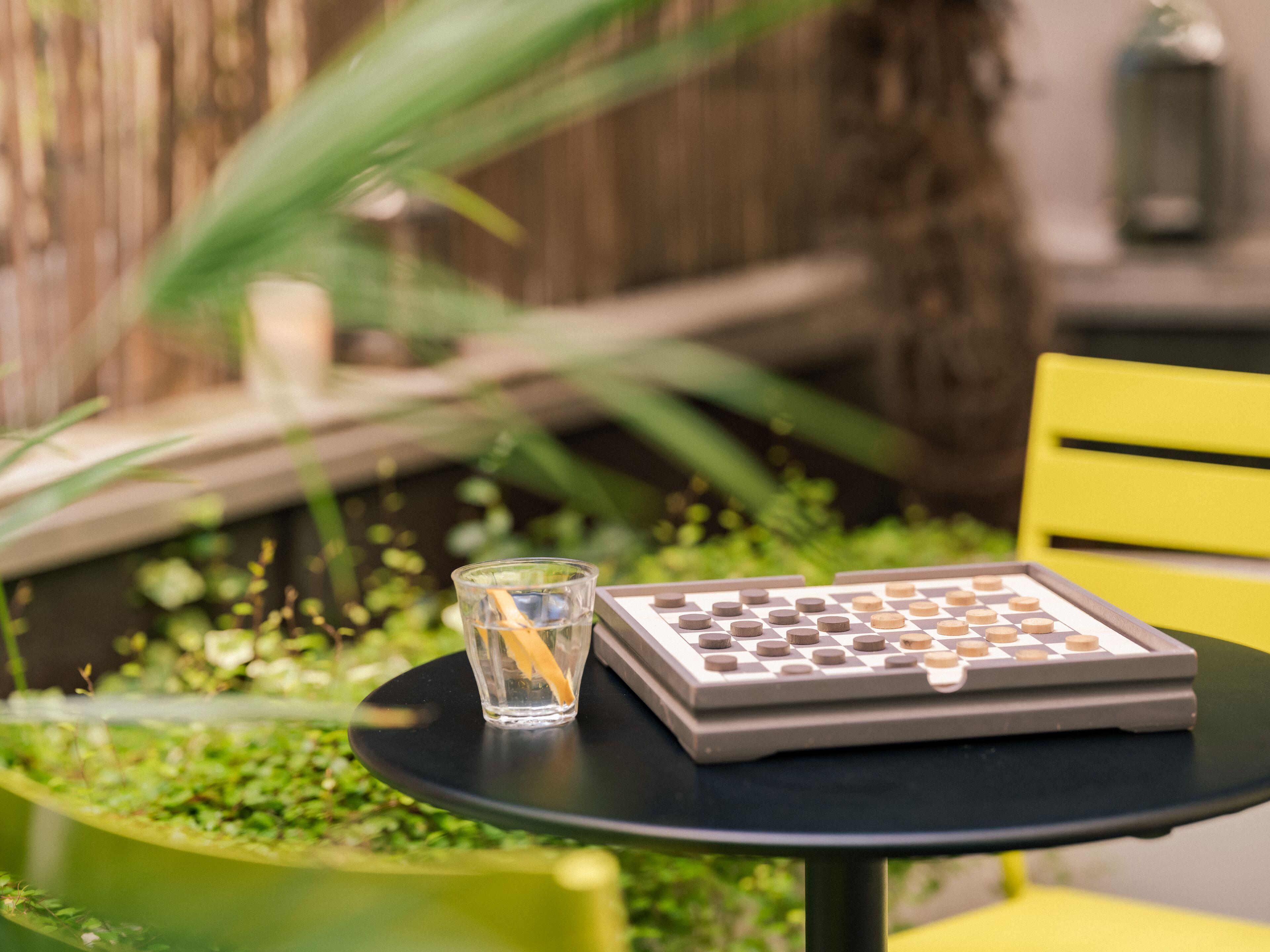 A table with a chess set and a glass of water.