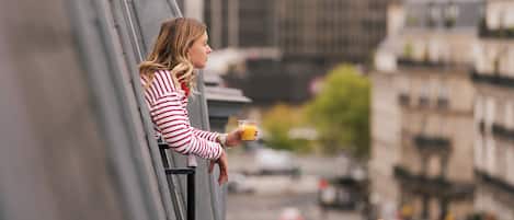 A person sitting on a balcony with a city view.